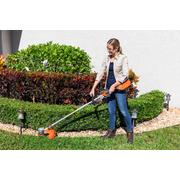 A person using a string trimmer to edge a garden lawn.