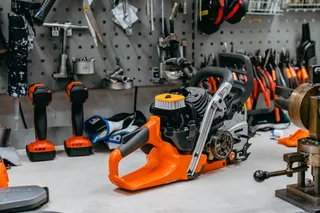 Chainsaw on a workbench surrounded by various tools and accessories in a workshop.