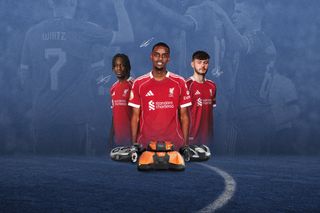 Three football players in Liverpool jerseys standing on a field with remote-controlled cars and a ball.