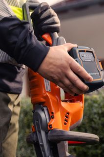 A person holding a Husqvarna product, showcasing the battery compartment.