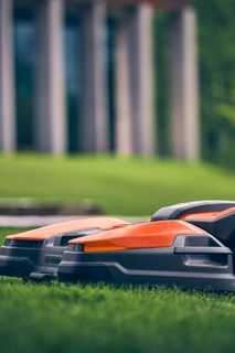Robotic lawn mower operating on a well-maintained lawn near a modern building.