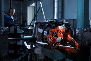A Husqvarna construction drill motor set up in a testing facility, with a person operating a computer in the background.