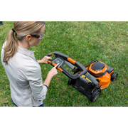 A person operating a lawn mower, adjusting settings on the control panel in a garden.