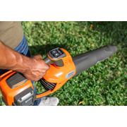 A person holding a leaf blower on a grassy area, showcasing the control panel.