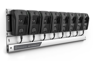 A Husqvarna charging rail with eight battery chargers mounted on it.