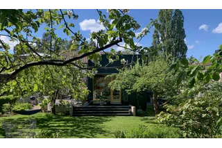 A lush garden with trees and a house in the background, showcasing a serene outdoor setting.